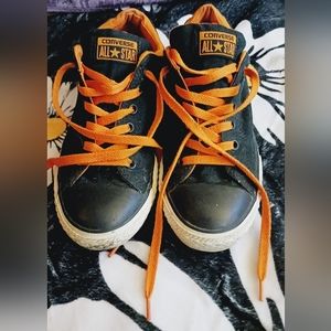 Black low top Converse with orange details.